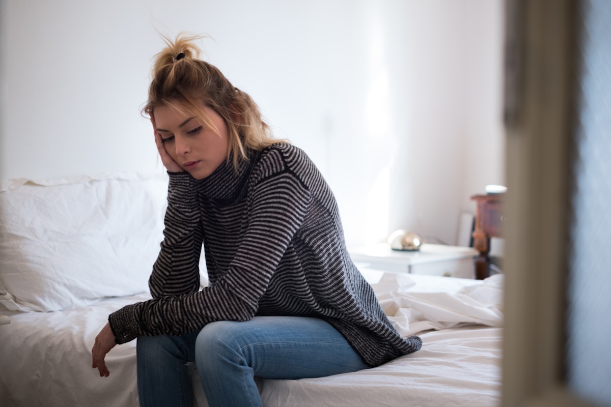 Kvinde sidder bekymret på sengen